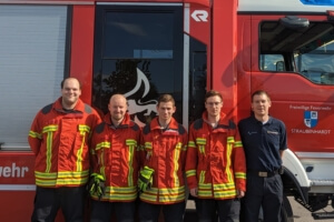 Die vier Lehrgangsteilnehmer Niklas Bauer, Thomas Wuhrer, Leon Gehrke, Jan Gehrig und Straubenhardter Ausbilder Robin Geisert vor einem Feuerwehrfahrzeug.