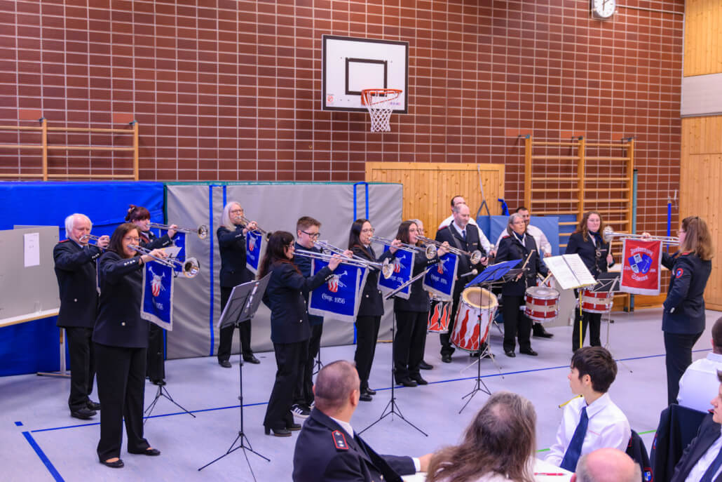 Der Fanfarenzug (15 Mitglieder) der Feuerwehr spielt ein Musikstück in einer Turnhalle